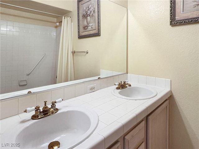 full bathroom with double vanity, a shower with curtain, a sink, and a textured wall