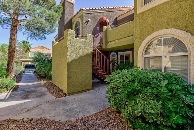 view of side of property featuring a tiled roof, stairs, and stucco siding