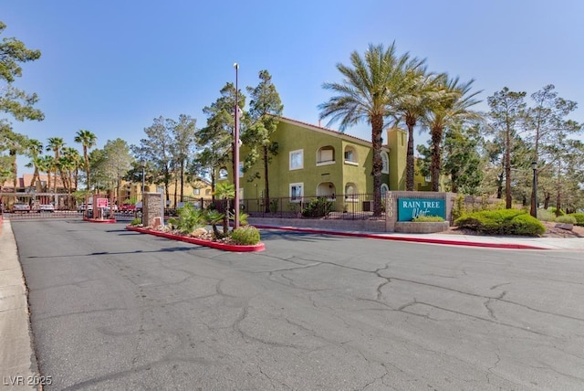 view of road featuring street lighting, curbs, sidewalks, and a gated entry