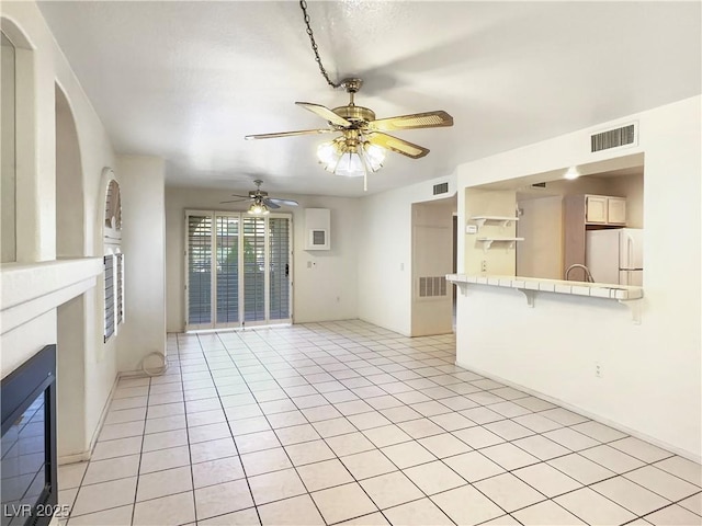 unfurnished living room featuring light tile patterned flooring, a glass covered fireplace, and visible vents