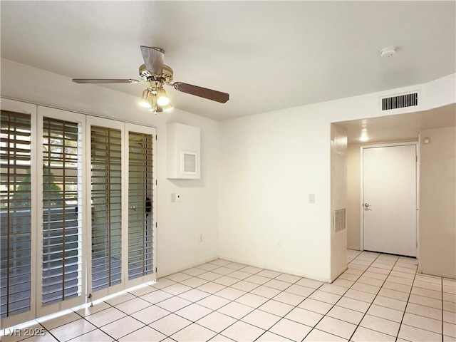 empty room featuring a ceiling fan, visible vents, and light tile patterned floors