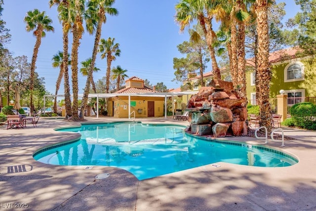 community pool with a patio area and fence