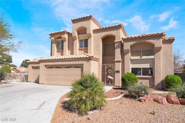 mediterranean / spanish-style house with a gate, concrete driveway, and stucco siding