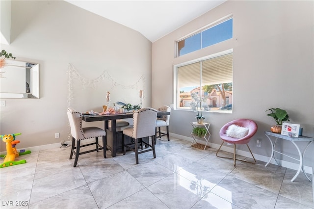 dining room with marble finish floor, baseboards, and vaulted ceiling