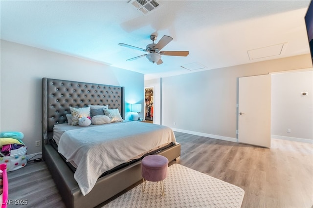 bedroom featuring light wood-style floors, attic access, visible vents, and baseboards