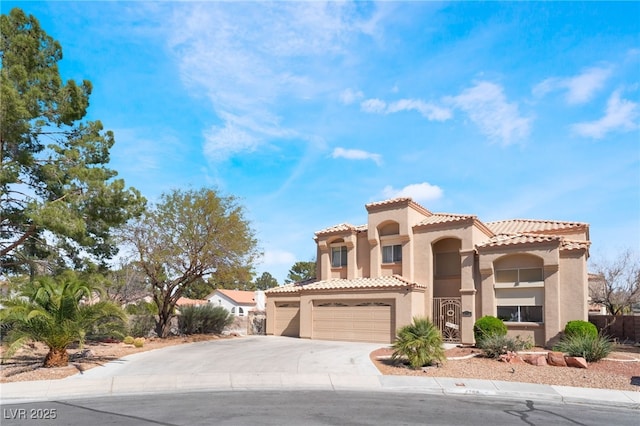 mediterranean / spanish house featuring concrete driveway, an attached garage, a tiled roof, and stucco siding