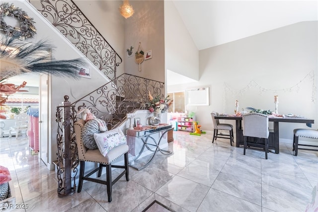 interior space featuring high vaulted ceiling, marble finish floor, and baseboards