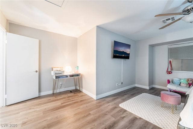 living area with ceiling fan, wood finished floors, visible vents, and baseboards