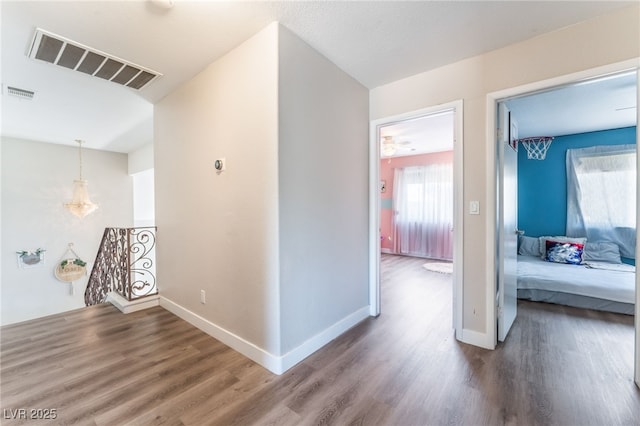 corridor with wood finished floors, plenty of natural light, an upstairs landing, and visible vents