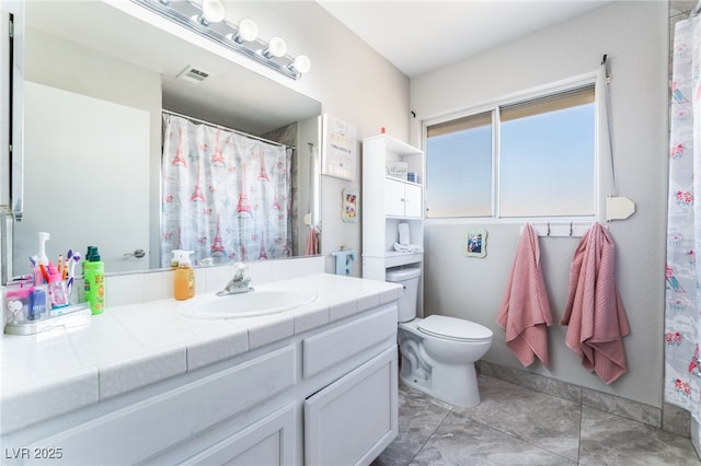 bathroom with toilet, vanity, and visible vents