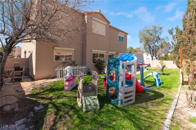 view of jungle gym with a lawn and fence