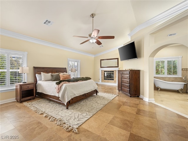 bedroom with visible vents, ornamental molding, baseboards, and a glass covered fireplace