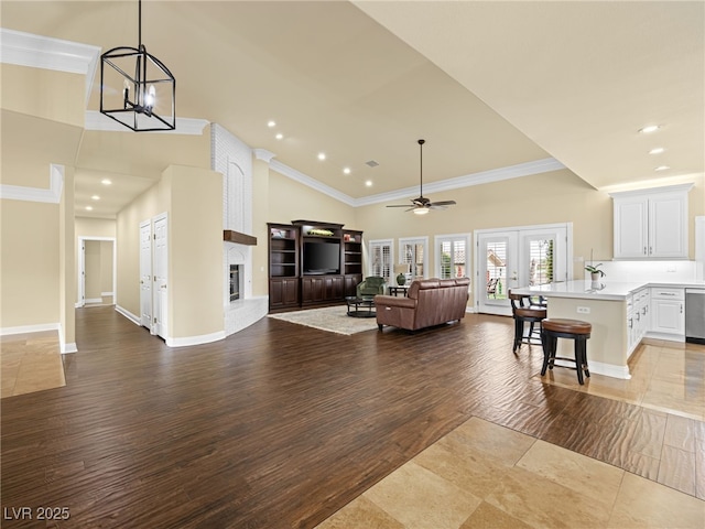 living area with ornamental molding, wood finished floors, recessed lighting, french doors, and a fireplace