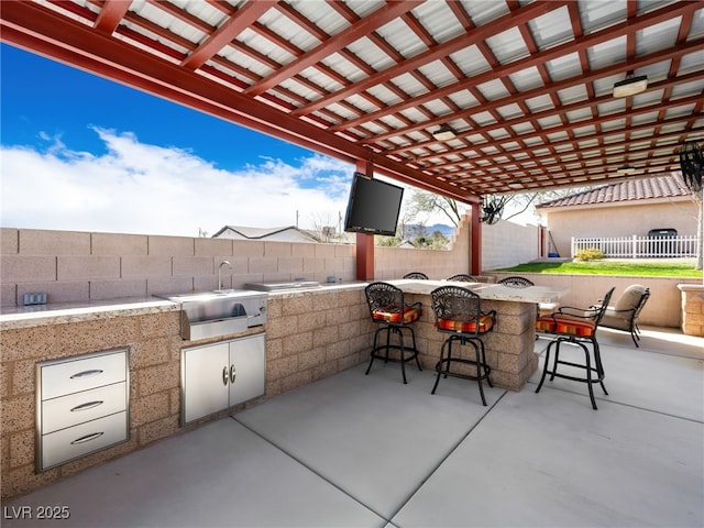 view of patio / terrace with an outdoor kitchen, outdoor wet bar, and a fenced backyard