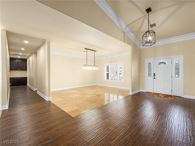 entrance foyer with crown molding, wood finished floors, and visible vents