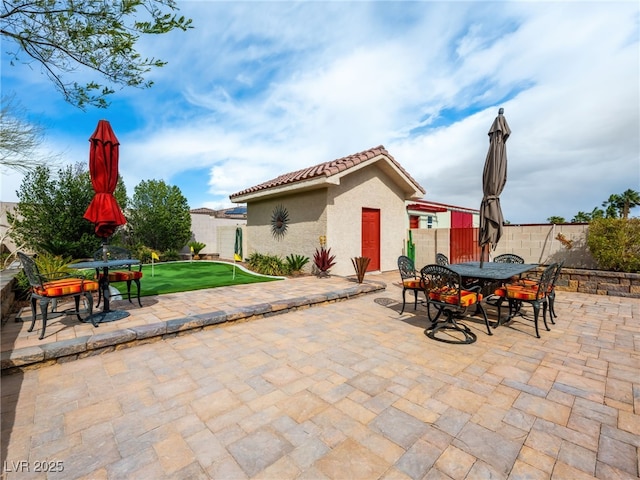 view of patio with an outbuilding, outdoor dining area, and a fenced backyard