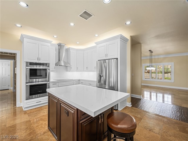 kitchen with visible vents, light countertops, stainless steel appliances, white cabinetry, and wall chimney exhaust hood