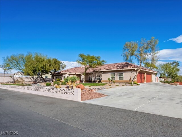 view of front of property with stucco siding, fence, concrete driveway, a garage, and a tiled roof