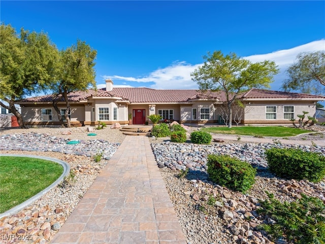 ranch-style house with a tile roof, stucco siding, and a chimney