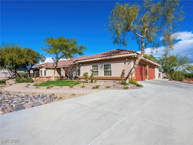 view of front of home featuring stucco siding, an attached garage, a tile roof, and concrete driveway