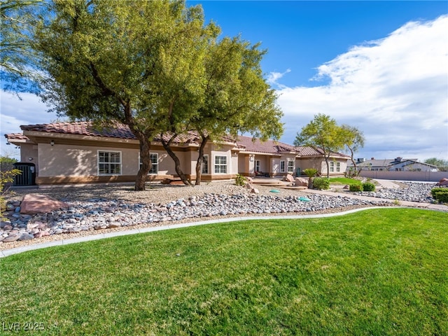 view of front of house with a front lawn, a tiled roof, and stucco siding