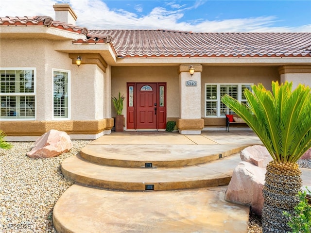 property entrance featuring a tiled roof and stucco siding