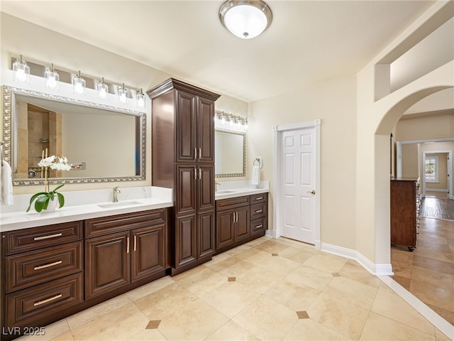 full bath featuring tile patterned floors, a sink, baseboards, and double vanity