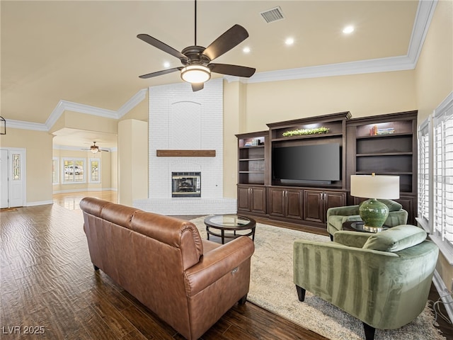 living room with a wealth of natural light, visible vents, crown molding, a brick fireplace, and dark wood-style flooring