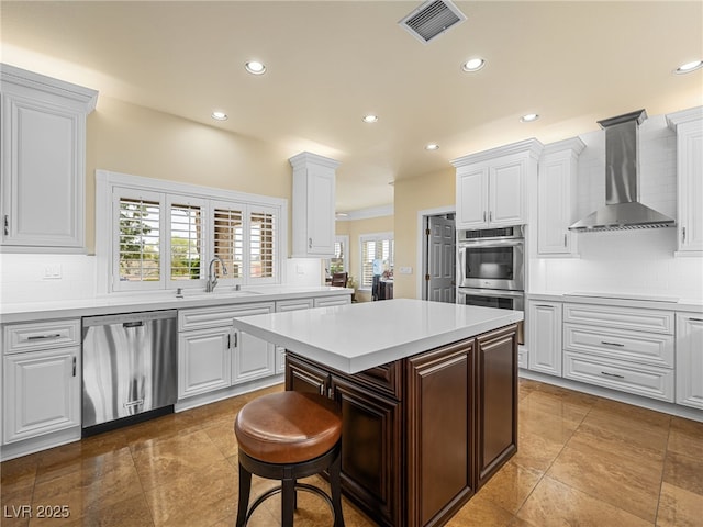 kitchen featuring visible vents, tasteful backsplash, stainless steel appliances, wall chimney exhaust hood, and light countertops