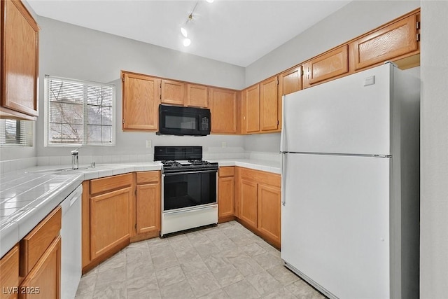 kitchen featuring tile countertops, white appliances, and a sink