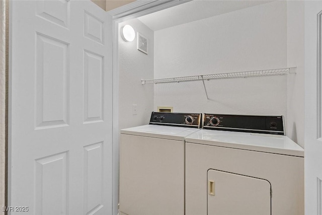 laundry room with laundry area, separate washer and dryer, and visible vents