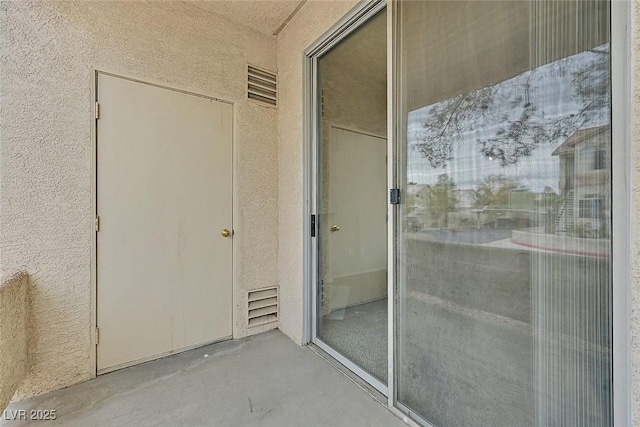 view of exterior entry featuring visible vents and stucco siding