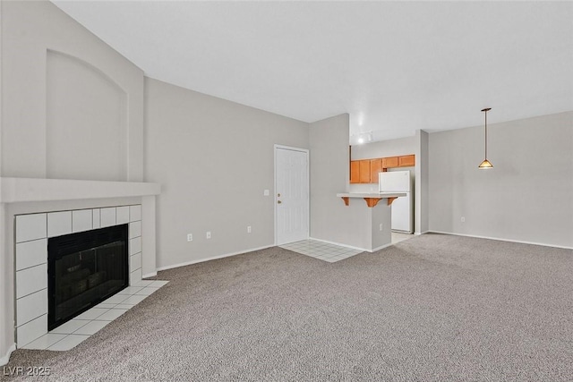 unfurnished living room with light carpet, a tile fireplace, and baseboards