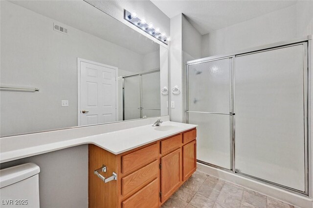 bathroom featuring vanity, a shower with shower door, toilet, and visible vents