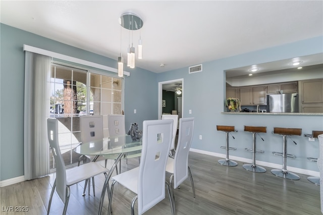 dining space featuring ceiling fan, wood finished floors, visible vents, and baseboards