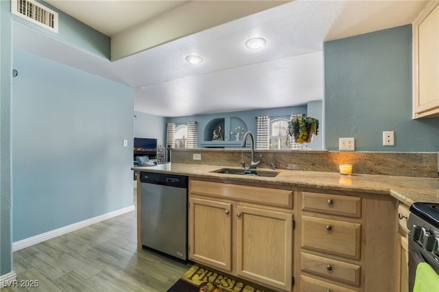 kitchen with visible vents, stainless steel dishwasher, open floor plan, a sink, and a peninsula