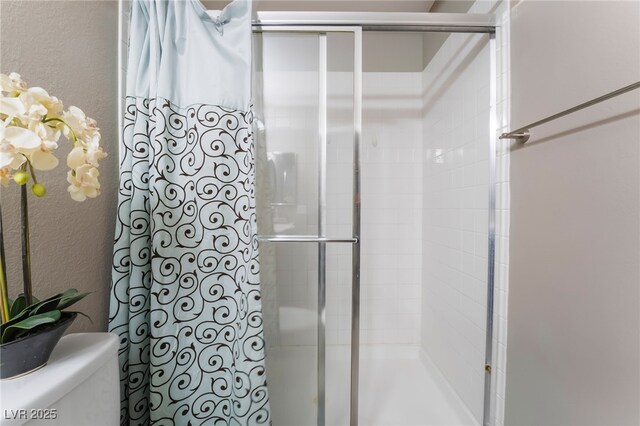 full bath with a stall shower, a textured wall, and toilet