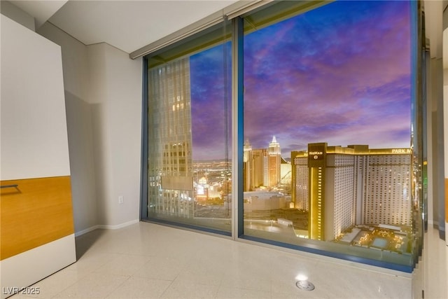 interior space with a view of city, baseboards, and a wall of windows