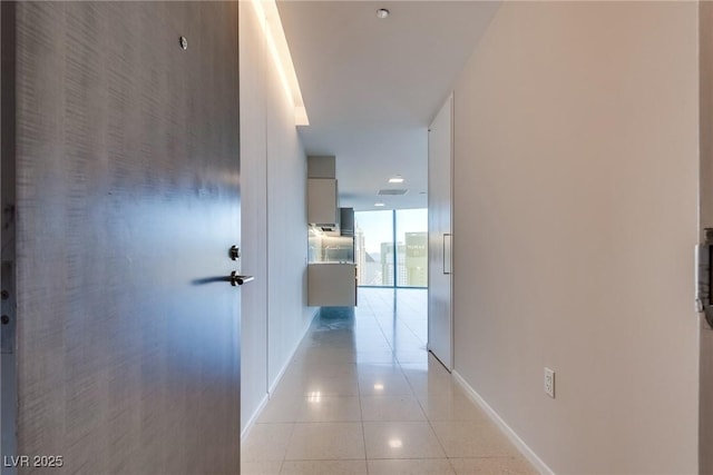 hallway featuring baseboards and light tile patterned flooring