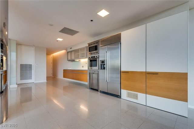 kitchen with built in appliances, visible vents, baseboards, light countertops, and glass insert cabinets