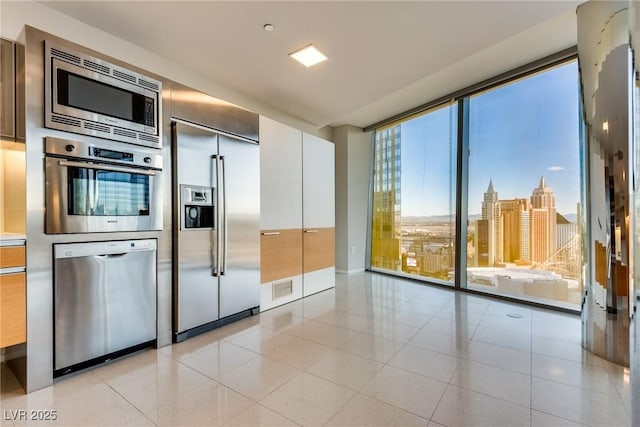 kitchen with light tile patterned floors, visible vents, built in appliances, a view of city, and floor to ceiling windows