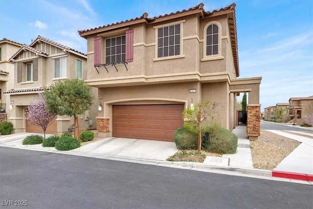 mediterranean / spanish-style house with a garage, driveway, a tiled roof, and stucco siding