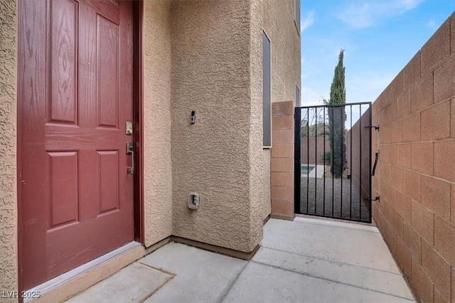 entrance to property featuring fence, a gate, and stucco siding