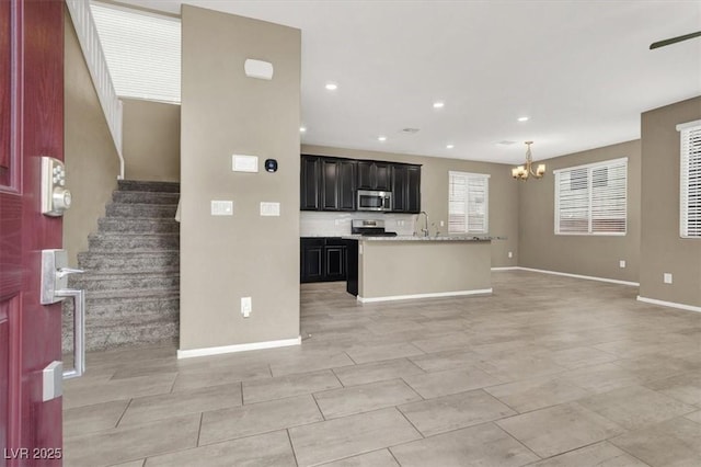 kitchen featuring a notable chandelier, light countertops, appliances with stainless steel finishes, open floor plan, and dark cabinets