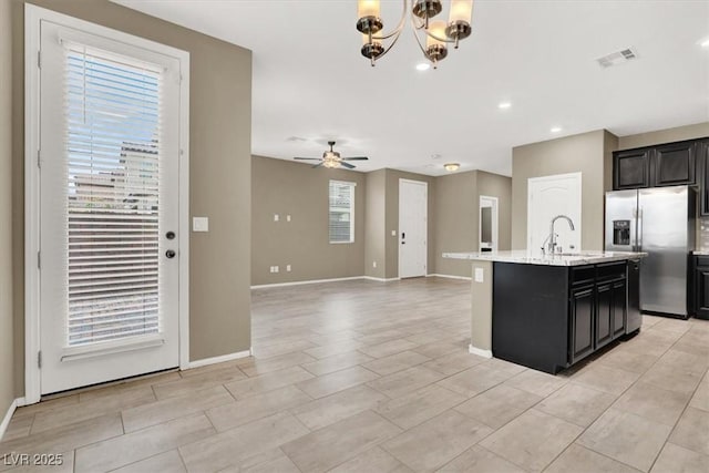 kitchen with stainless steel fridge, baseboards, a sink, and ceiling fan with notable chandelier