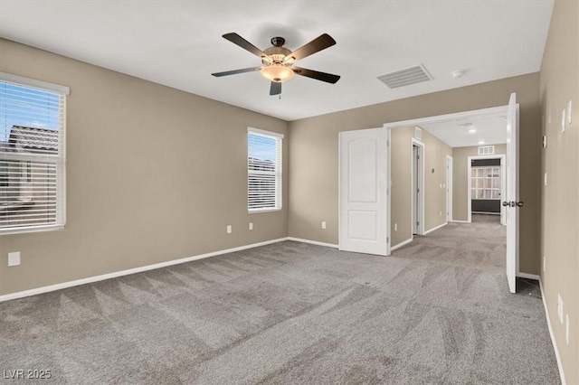 carpeted empty room with a ceiling fan, visible vents, and baseboards