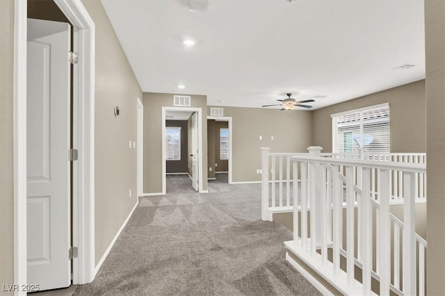 hallway featuring a wealth of natural light, visible vents, and an upstairs landing