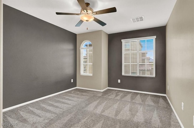 spare room with carpet floors, baseboards, visible vents, and a ceiling fan