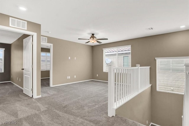 spare room with carpet floors, a healthy amount of sunlight, visible vents, and baseboards