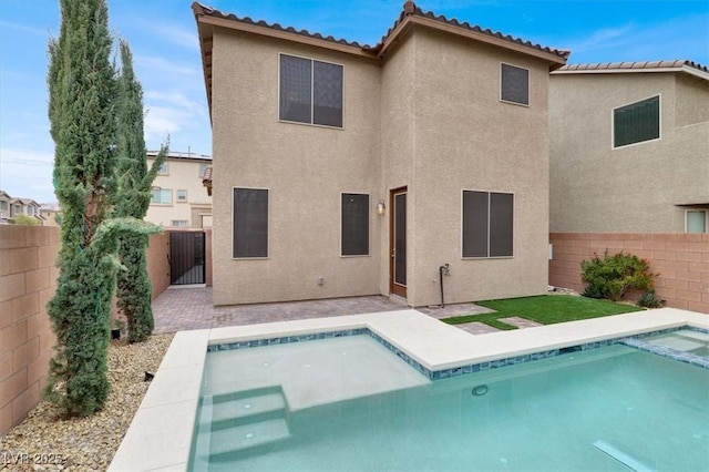 rear view of house with a tiled roof, a fenced backyard, a fenced in pool, and stucco siding